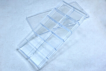 clear plastic box, divided into sections on a gray, rough, uneven surface