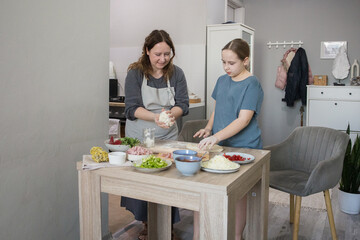 Lifestyle portrait of daughter cooking pizza with her mother in the kitchen