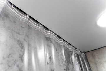 Modern gray curtains are hanging from a ceiling track system, adding a touch of elegance and style to the interior design of a contemporary apartment