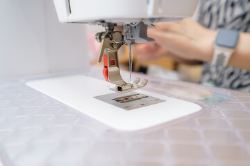 Sewing machine in action with skilled hands creating intricate fabric patterns during a crafting session at home