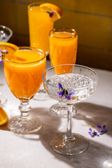 Elegant crystal glasses and orange juice cocktails with edible flowers