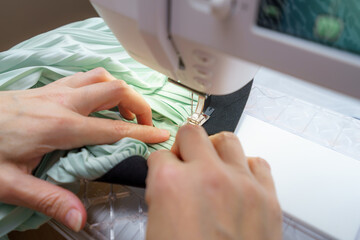 Sewing process at a crafting table with fabric and a sewing machine focusing on delicate garment...