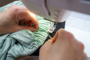 Sewing a delicate pleated fabric at a sewing machine in a well-lit workspace