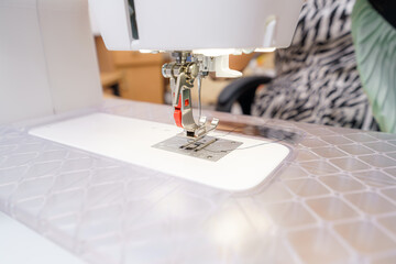 Sewing machine in use at a crafting workshop during daytime, focusing on stitch creation and fabric manipulation