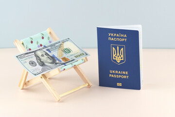 Ukraine passport and chaise lounge with dollars and globe on a light background.