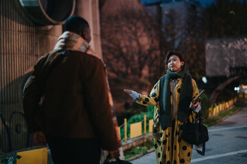 Two individuals engaging in a conversation in an outdoor evening urban environment. Depicts a...