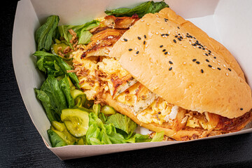 A tasty sandwich with savory ingredients served with fresh greens and pickles