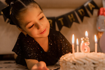 a little brunette girl makes a wish and blows out the candles on the cake