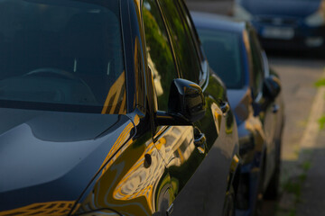 Fototapeta premium There are two cars that are parked closely together next to one another on the side of the busy road, taking up some space