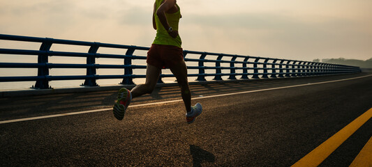 Healthy lifestyle woman runner running on seaside bridge