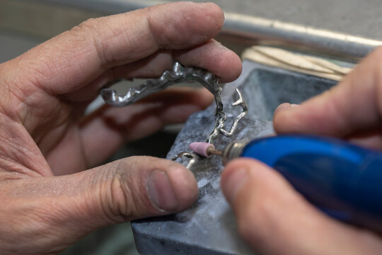 Cr&eacute;ation d'un dentier sur stellite avec la partie pon&ccedil;age dans les main d'un technicien de laboratoire