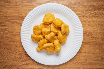 Crispy golden nuggets artfully arranged on a white plate, evoking comfort and indulgence