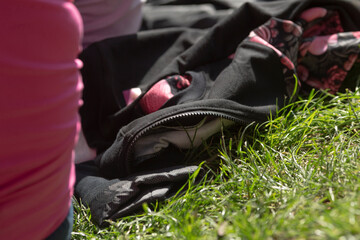 A person wearing a bright pink shirt is standing beside a bag placed on the grass, which adds a...