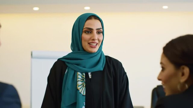 Smiling Muslim woman in hijab presenting business strategies to partners during a meeting in an office