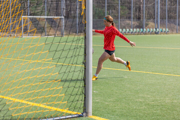 Sporty girl scores a goal into the goal. Football concept. Girl on the football field.