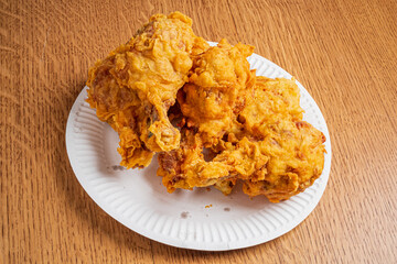 Golden fried chicken pieces stacked on a paper plate, ready to be enjoyed at a gathering