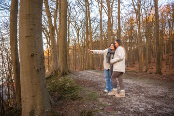 Fototapeta premium Two women in the forest. Woman pointing at the scenery. People in nature.