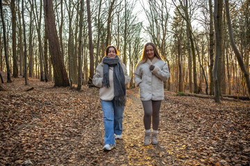 Fototapeta premium Two female friends on a walk in the forest. Friends walking through the forest. People in nature.