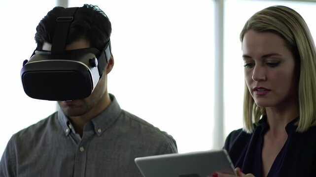 Portrait of young man wearing VR glasses and woman monitoring on tablet with interactive action