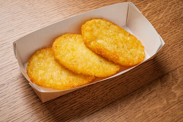Deliciously cooked hash browns rest in a simple paper tray, ready to be enjoyed with breakfast