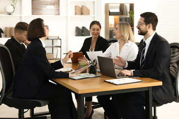 Coworkers working together at wooden table in office