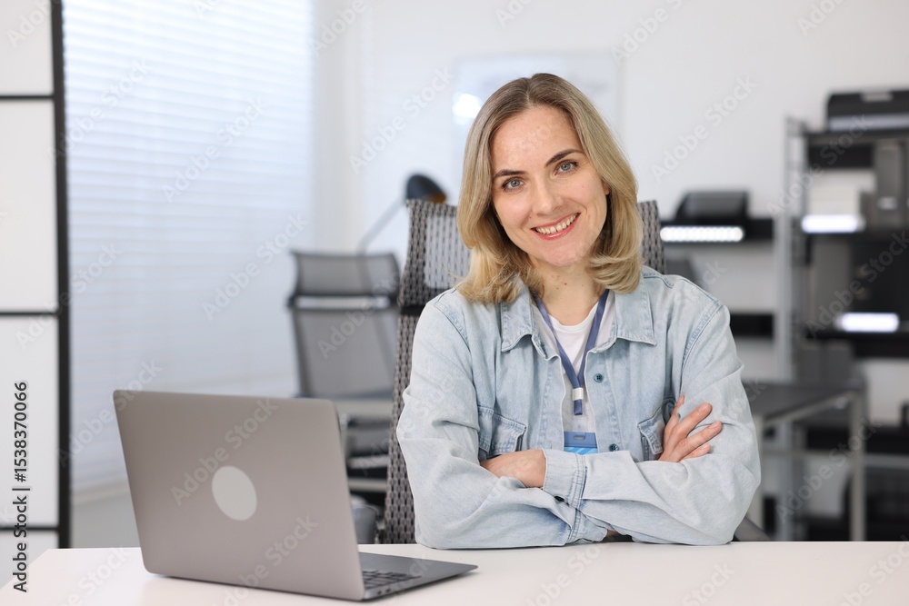 Poster portrait of smiling engineer working with laptop at table in office