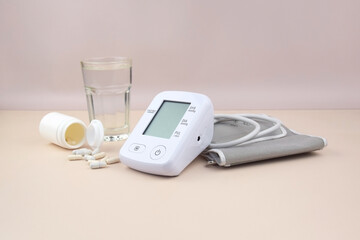 Digital blood pressure tonometer and pack of pills on a light background with copy space.