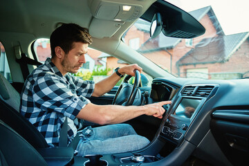Man sitting in car and pressing engine start button. Starting vehicle using modern ignition...