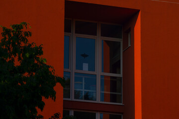 Obraz premium There is a striking red building that features a large window, and in front of it, there stands a beautiful green tree