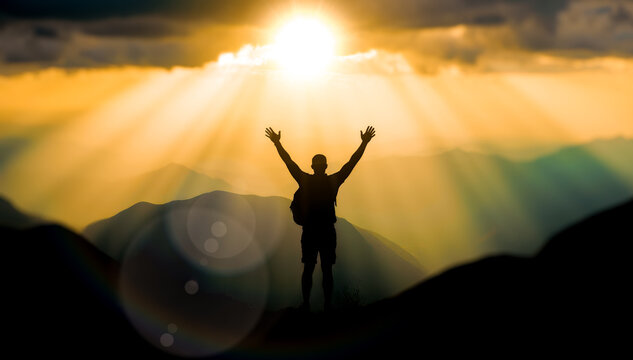 Silhouette of man with arms raised on mountain top at sunrise, a concept for freedom, spiritual awakening and new beginnings