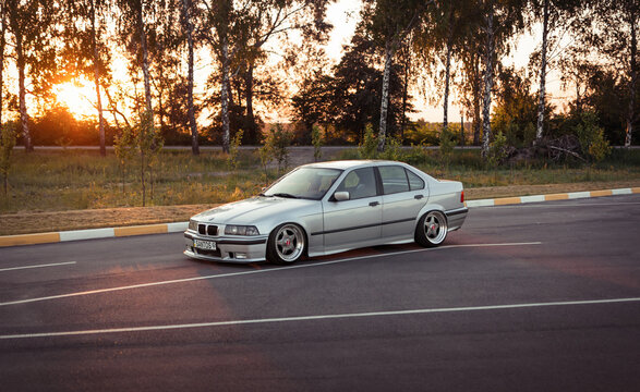 BMW 3-series E36 sedan in parking lot at sunset. Silver low car on a road in countryside in the end of the day. Bucha, Ukraine - June 08 2015.