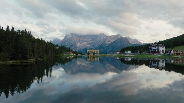 Lago di Misurina natural alpine lake in Dolomites surrounded by mountains and coniferous forests in evening, Drone shot, Panoramic view