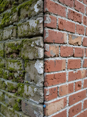 a close-up of two brick walls meeting at a corner. The left wall is old, covered in moss with rough cement, while the right wall looks newer with red bricks and fresh mortar.