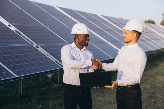Engineers Shaking Hands in Front of Solar Panels - Powered by Adobe