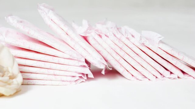 Feminine hygiene products resting near white rose, symbolizing women's wellness, self care, and natural purity against minimalist white backdrop
