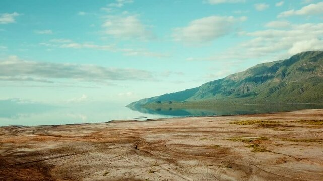 4k drone footage of the shores of Lake Natron in Kenya with mirror-like reflections of the hills and landscape of Tanzania