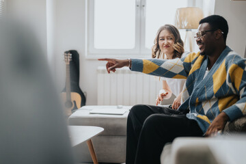 A diverse couple enjoys time together in a cozy home setting featuring a guitar and comfortable furnishings, emphasizing connection and warmth.