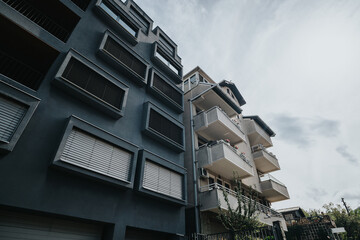 Modern apartment buildings with angular designs and balconies, highlighted by a cloudy sky...