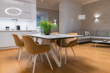Luxurious interior featuring a marble top dining table, mustard chairs, minimalist kitchen, gray...