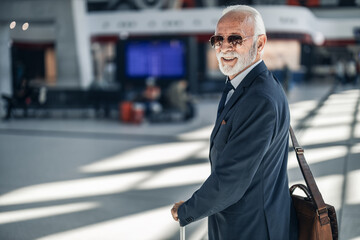Elderly Businessman in Suit Smiling at Airport with Briefcase