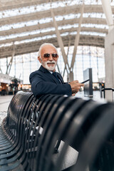 Confident Businessman Relaxing in Airport Seating with Stylish Sunglasses