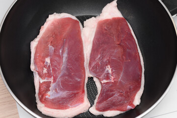 Two pieces of duck breast fried in a pan