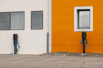 Two electric vehicle charging stations against colorful building