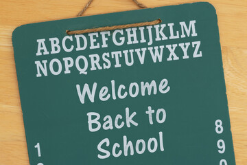 Welcome Back to School on a green chalkboard on a wood desk