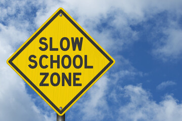 Slow School Zone yellow warning sign with cloudy sky