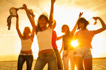  group of young people happily dancing on the seashore at sunset