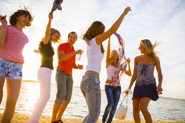  group of young people happily dancing on the seashore at sunset
