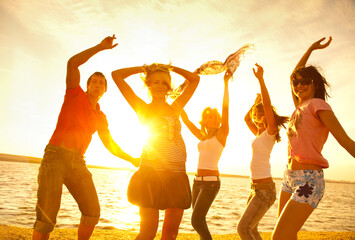  group of young people happily dancing on the seashore at sunset