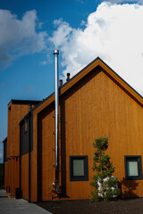 Modern wooden house with chimney under a bright blue sky