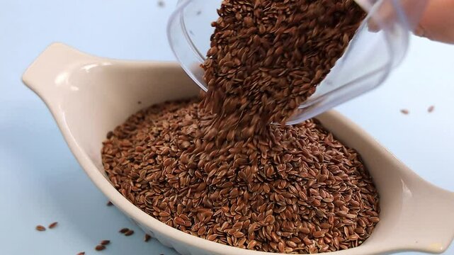 Healthy uncooked raw flax seeds dropping in a bowl. FullHD footage